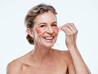 Image showing Lets do a little reversing. a mature woman wearing under-eye gel patches while posing against a white background.