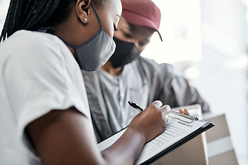 Image showing Right on time as promised. a masked young woman signing for a delivery received at home.