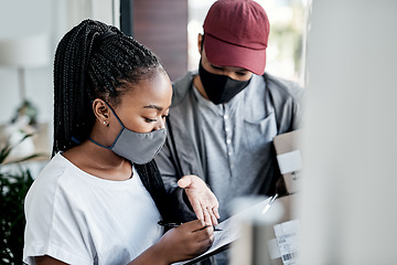 Image showing Handled with the care your package deserves. a masked young woman signing for a delivery received at home.