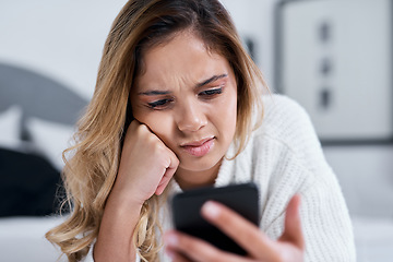 Image showing Why would she post that. a young woman using her cellphone while lying on her bed.