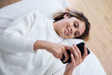 Image showing So many people shared my post already. a young woman using her cellphone while lying on her bed.