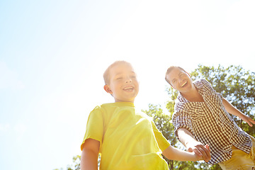 Image showing Look at this. Cute young boy pulling his dad by the hand to show him something outdoors.