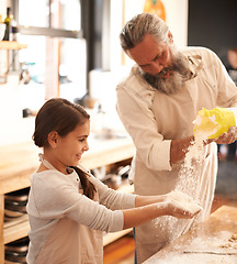 Image showing A shower of flour. a girl and her grandfather baking together in the kitchen.