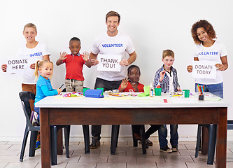 Image showing Help us help them. Portrait of volunteers holding up signs while working with little children.