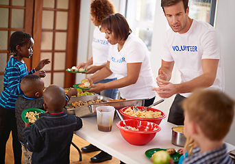 Image showing Making sure they get a healthy meal. volunteers serving food to a group of little children.