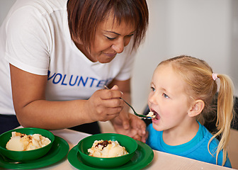 Image showing Open up. a volunteer feeding a little girl at a youth center.