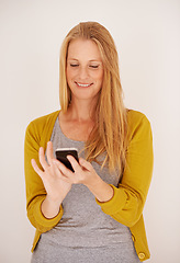 Image showing Downloading a new app is so easy. a happy woman sending a text message on her mobile phone.