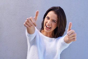 Image showing Youre a superstar. Portrait of a happy young woman standing against a gray background and giving thumbs up.