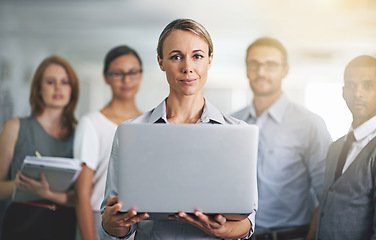 Image showing I present to you...Portrait of a businesswoman holding a laptop with her colleagues blurred in the background.