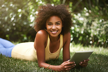 Image showing Spending some time online in the outdoors. an attractive young woman using her digital tablet while lying on the grass.