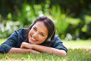 Image showing The best way to spend a sunny afternoon. Portrait of an attractive young woman lying on the grass and listening to music.