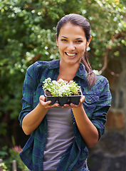 Image showing Some new arrivals for the garden. Portrait of an attractive young woman holding a punnet of seedlings.