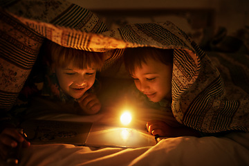 Image showing Brothers are friends for life. Two young brothers coloring in pictures while underneath their blanket after their bedtime.