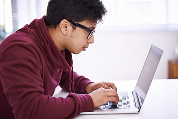 Image showing No distractions because Im hard at work. a handsome young man working on his laptop in an office.