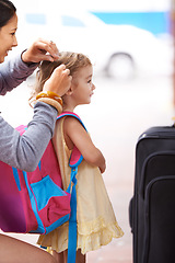 Image showing Daughter are little girls that grow up to become your friend. A mother tying her daughters hair while waiting for their transport to arrive.