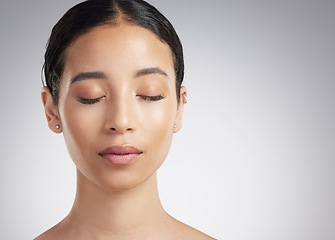 Image showing A beautiful young mixed race woman with glowing skin posing against grey copyspace background. Hispanic woman with natural looking eyelash extensions finds inner peace in a studio