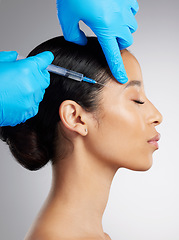 Image showing Closeup of a gorgeous mixed race woman getting botox filler. Hispanic model getting filler to reduce wrinkles against a grey copyspace background in a studio