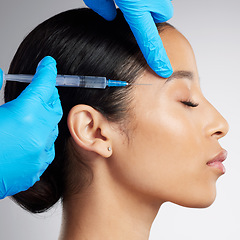 Image showing Closeup of a gorgeous mixed race woman getting botox filler. Hispanic model getting filler to reduce wrinkles against a grey copyspace background in a studio