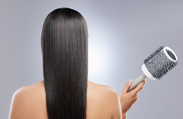 Image showing How to get sleeker than sleek hair. Rearview shot of a woman holding a blow-dry brush against a grey background.