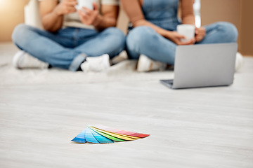 Image showing Everything is about colour. Closeup shot of colour swatches on the floor with an unrecognisable couple using a laptop in the background while moving house.