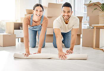 Image showing This is where we make an exciting new start. Portrait of a young couple rolling out a carpet together in their new home.