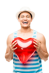 Image showing The heart can swell to twice its size. a young man holding a heart balloon against a studio background.