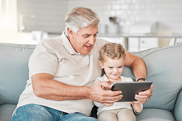 Image showing A child needs a grandparent. an adorable little girl using a digital tablet while sitting at home with her grandfather.