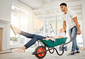 Image showing Well always be young at heart. Full length shot of a handsome young man feeling playful while pushing his girlfriend in a wheelbarrow at home.