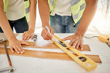 Image showing Adding some texture to the home. two unrecognisable construction workers standing together and using a ruler to measure a beam of wood.