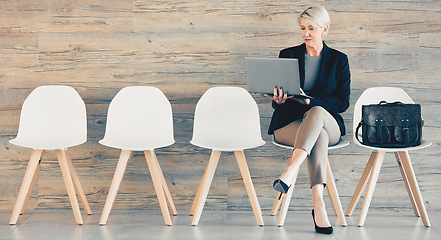 Image showing Every time you conquer one it makes you stronger. a mature businesswoman using a laptop while waiting in line at an office.