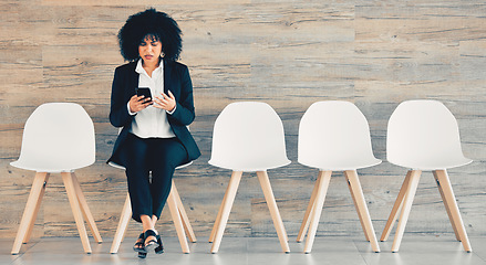 Image showing Successful people keep moving. a young businesswoman using a phone while waiting in line at an office.