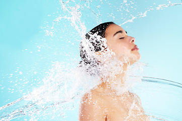 Image showing Real women take care of their skin. a beautiful young woman being splashed with water against a blue background.