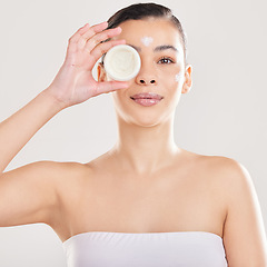 Image showing Keep your skin moisturised. a young woman applying a cream to her face against a grey background.