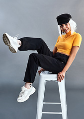 Image showing My look, my way. Studio shot of a beautiful young woman sitting on a stool against a grey background.