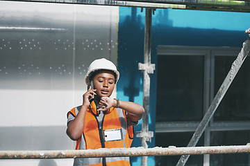 Image showing Staying on track with the days schedule. a young woman talking on a cellphone and checking the time while working at a construction site.