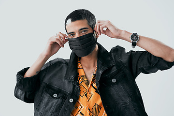 Image showing Who said face masks cant be fashionable. Studio shot of a young man putting on a face mask against a grey background.