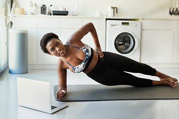 Image showing Planking creates definition in your abs. a young woman using a laptop while exercising at home.