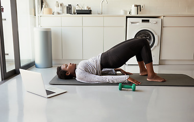 Image showing Include exercise in your self-care routine. a young woman using a laptop while exercising at home.