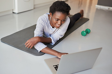 Image showing Browsing through a vast digital archive of fitness videos. a young woman using a laptop while exercising at home.