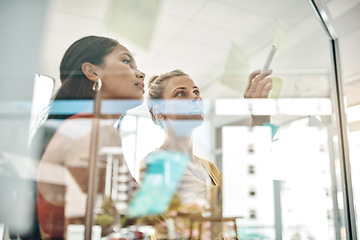 Image showing Formulating clear objectives and goals. two businesswomen brainstorming with notes on a glass wall in an office.