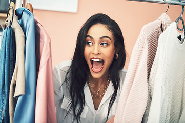 Image showing Its competition time and you this collection could be yours. a young woman sticking her head in between items on a clothing rail.