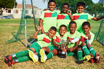 Image showing Players win games, teams win championships. Portrait of a boys soccer team posing with their trophy on a sports field.