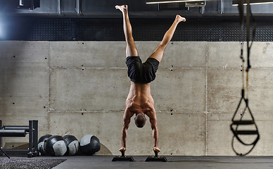 Image showing A muscular man in a handstand position, showcasing his exceptional balance and body control while performing a variety of exercises to enhance his overall body stability and strength in a modern gym