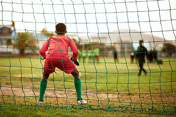 Image showing Will he be able to block the shot. Rearview shot of a young boy standing as the goalkeeper while playing soccer on a sports field.