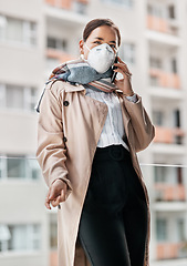 Image showing Weve adjusted well to the new norm. a young woman wearing a mask while talking on the phone on the balcony at home.