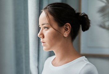 Image showing Im feeling a bit down today. a beautiful woman looking out the window at home.