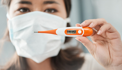 Image showing it is important to quarantine at the earliest signs of COVID-19. a woman holding up a digital thermometer that reads 41.5 degrees.
