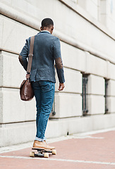 Image showing It doesnt matter how you get there, just get there. Rearview shot of a young businessman riding a skateboard through the city.