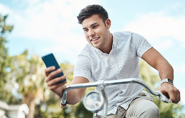 Image showing The more mobile the more he makes things happen. a young businessman using a smartphone while riding his bicycle in the city.