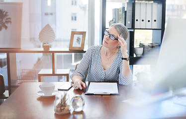 Image showing Am I making the right decisions for my business. a mature businesswoman going through paperwork in an office.